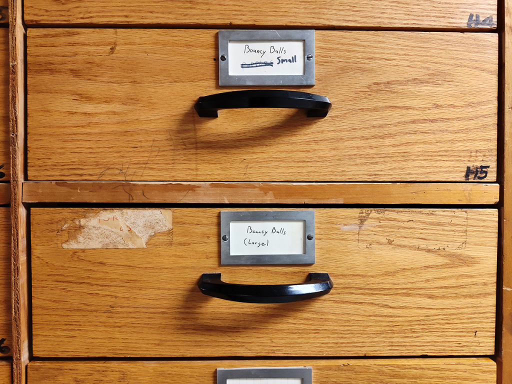 Wooden cabinet drawers, labeled "Bouncy Balls Small" and "Bouncy Balls (Large)"