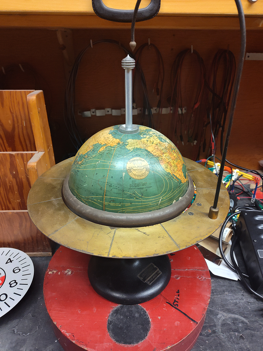 Globe with a tall axis post and Saturn-like ring.