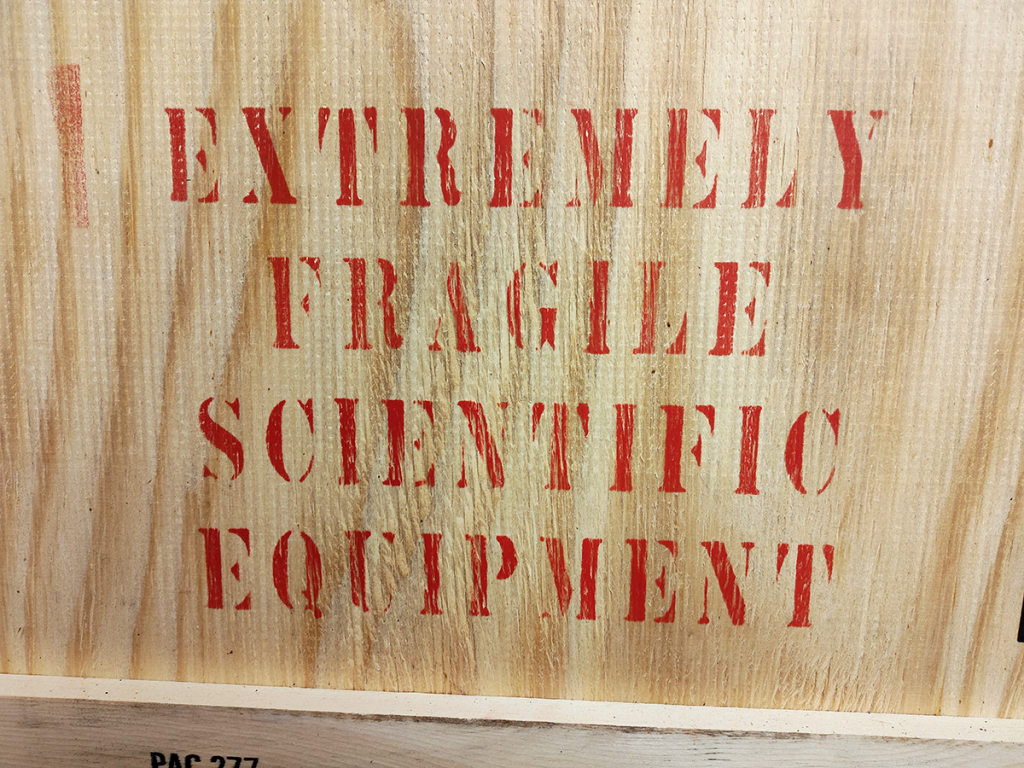 Crate stencil reading "Extremely Fragile Scientific Equipment"