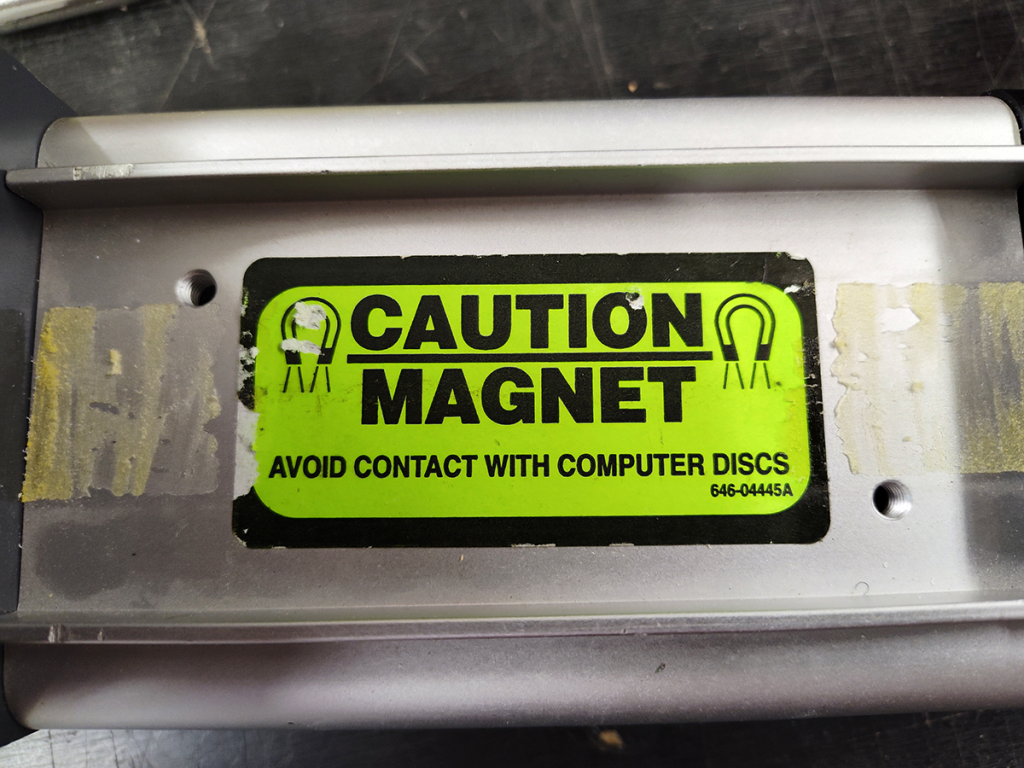 Bright green sticker reads "Caution / Magnet / Avoid contact with computer discs"