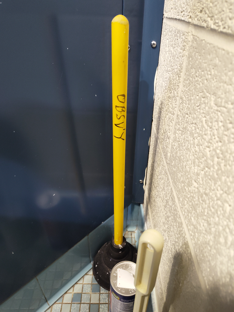 Plunger with yellow handle, with handwritten OBSV'Y on it.