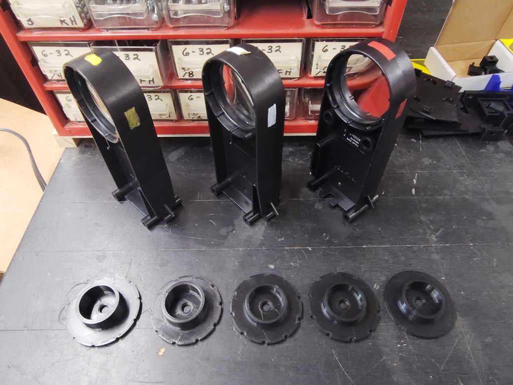 Lens holders and a series of 3D-printed parts, each very slightly different.