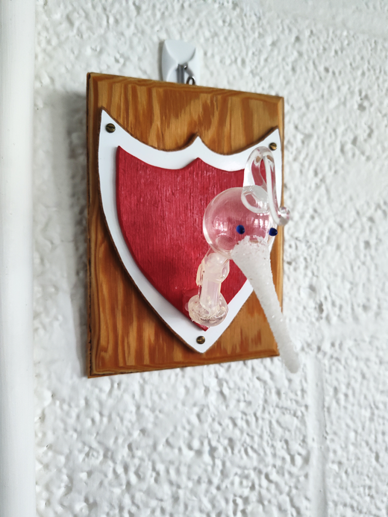 Broken drinking bird head, mounted as a trophy.