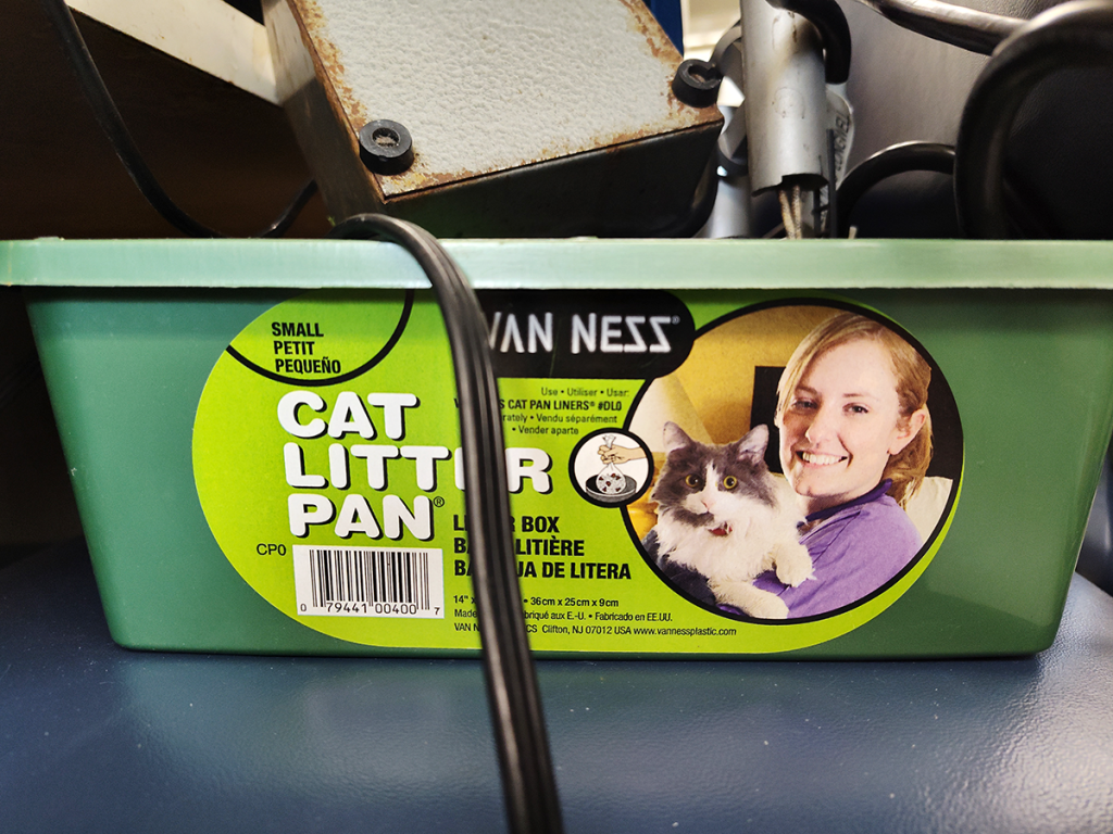 Green plastic cat litter pan filled with broken chemistry apparatus.