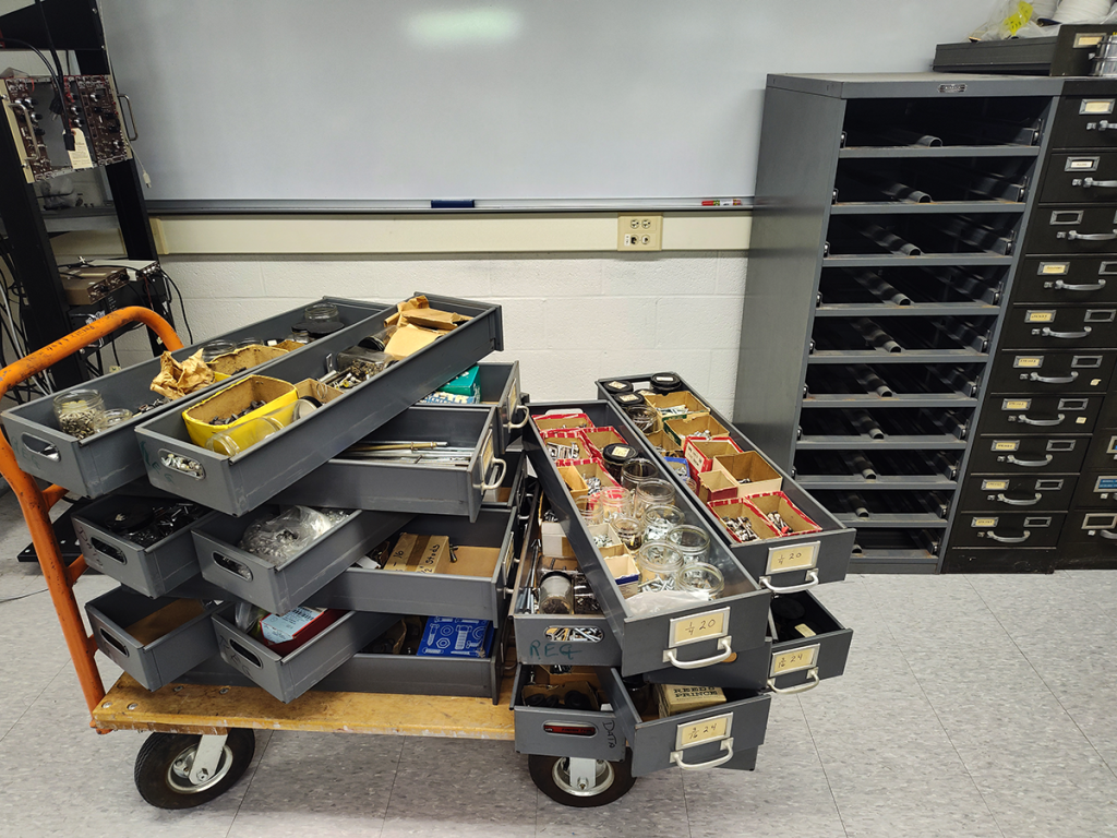Cart loaded with cabinet drawers, themselves loaded with a dense array of hardware.