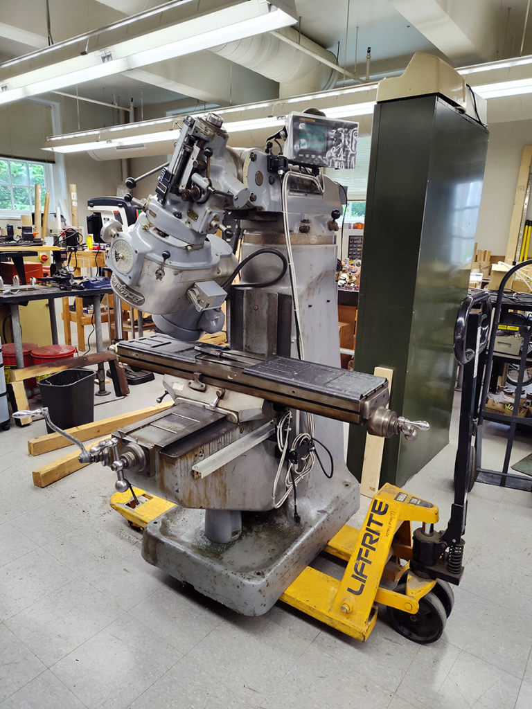 Milling machine loaded onto a pallet jack for moving.
