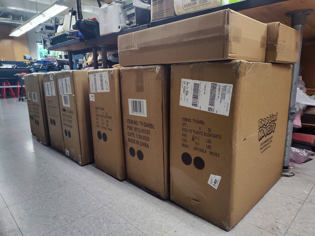 Brown cardboard boxes filled with toy blowdart guns.