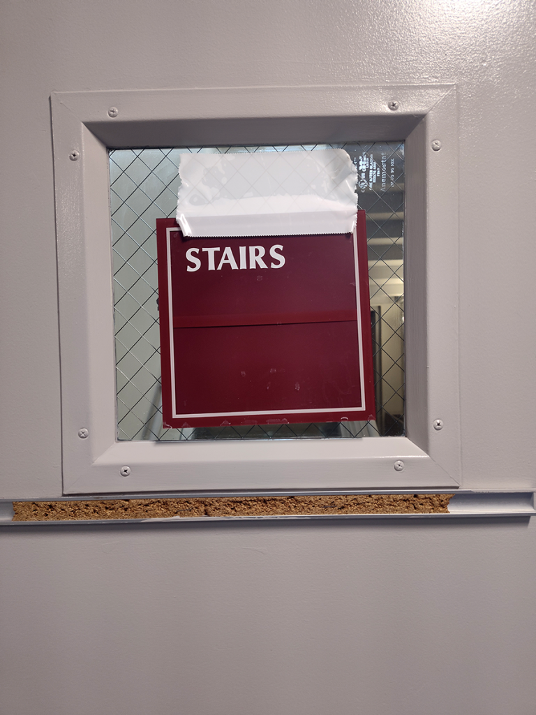 Wall sign indicating "Stairs" taped to a stairwell door.